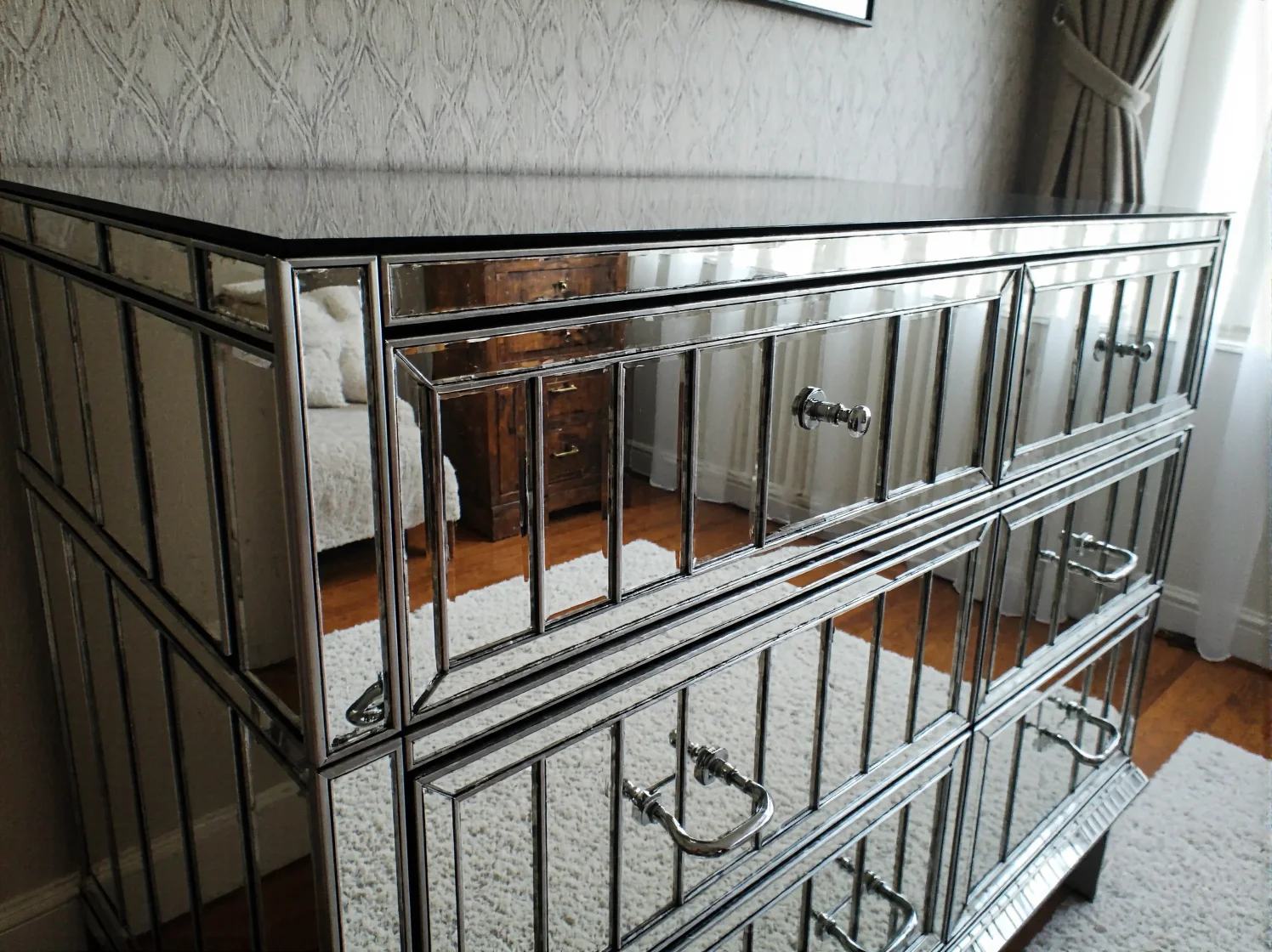 Zbliżenie na lustrzane fronty komody w stylu glamour z ozdobnymi, kryształowymi gałkami.